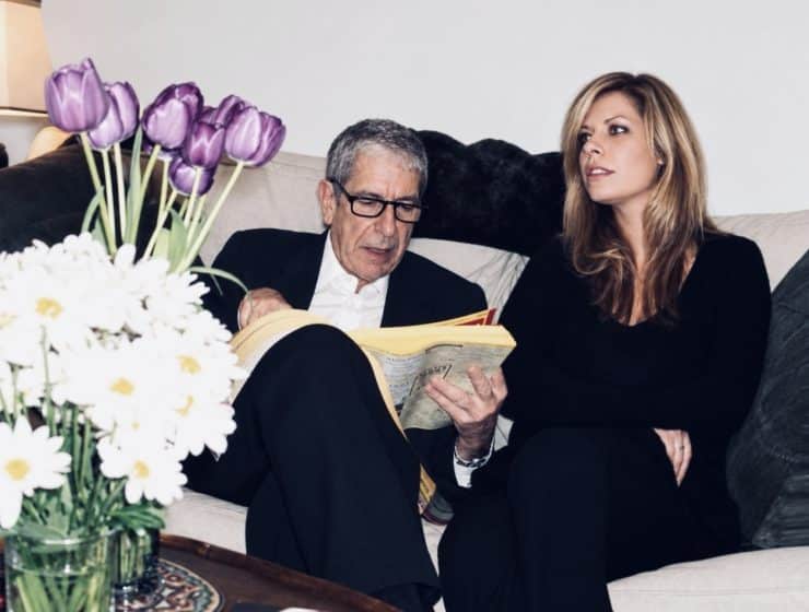 Leonard Cohen and Lonelle Selbo sit on Leonard's couch in his Montreal home while he looks up the number for the chicken place in the phone book.
