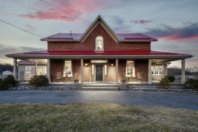 Red roofed farmhouse, dusk, lit from the inside. Classic Prince Edward County farmhouse.